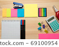 The top view of creative desk with office accessories, notebooks and colorful stickers. Wooden background with copy space for inscription. 69100954