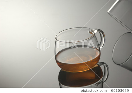 transparent glass cup with tea on a reflecting surface 69103629