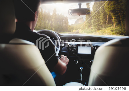 a man is driving in a car along the road against a man is driving in a car along the road against 69105696
