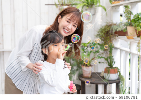 母親和她的孩子在陽台上玩肥皂泡 母親和她的孩子在陽台上玩肥皂泡 69106781
