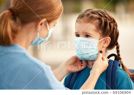 Woman putting medical mask on daughter before going to school 69106904