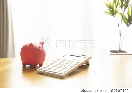 Piggy bank and calculator on the table Piggy bank and calculator on the table 69107301