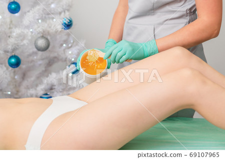 Young woman getting wax epilation of legs Young woman getting wax epilation of legs 69107965