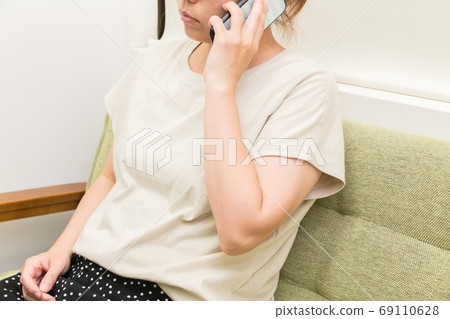 一個女人坐在沙發上打個電話 一個女人坐在沙發上打個電話 69110628