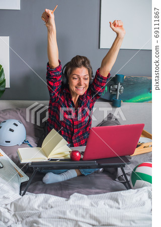 Woman working on computer remotely in bed Woman working on computer remotely in bed 69111867