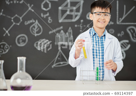Schoolboy mixing colorful liquids Schoolboy mixing colorful liquids 69114397