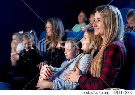 Mother holding daughter on knees in cinema. Mother holding daughter on knees in cinema. 69114878
