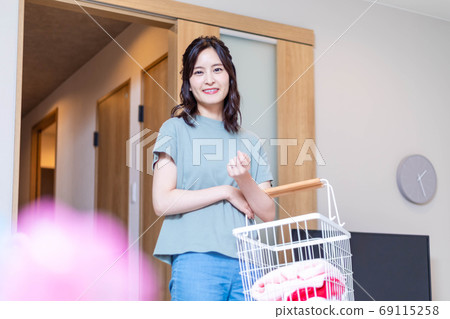 Young housewife carrying laundry at home 69115258