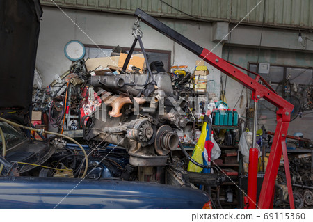 Engine hanging on crane hook on car repair service. Engine hanging on crane hook on car repair service. 69115360