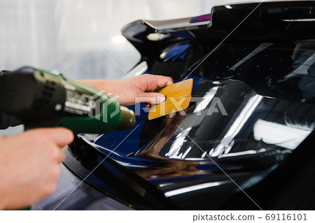 Car tinting. Worker applying tinting foil on car window Car tinting. Worker applying tinting foil on car window 69116101