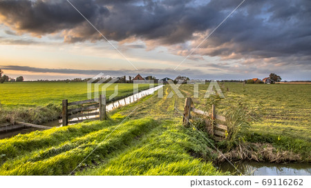 Cloudscape over gate in lowland meadow Cloudscape over gate in lowland meadow 69116262