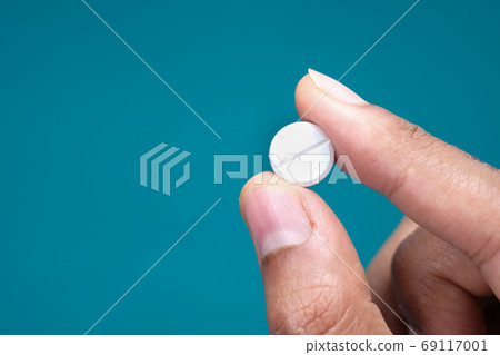 hand holding pills on green background with copy space  69117001