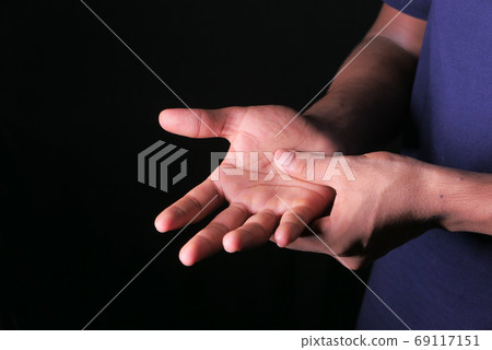 man with hand pain isolated in black. man with hand pain isolated in black. 69117151