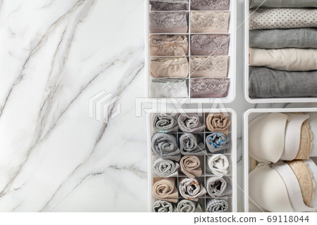 Womans underwear, pajamas and socks neatly folded and placed in closet organizer drawer divider on white marble table. Womans underwear, pajamas and socks neatly folded and placed in closet organizer drawer divider on white marble table. 69118044