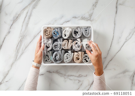 Woman hands placing organizer drawer divider with full of folded underwears and socks. 69118051
