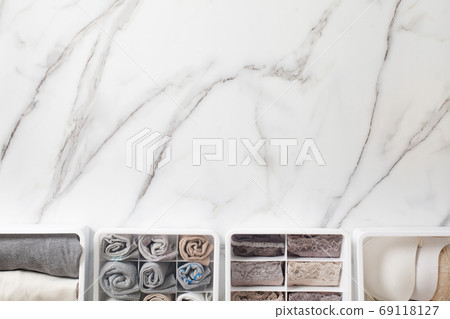 Womans underwear, pajamas and socks neatly folded and placed in closet organizer drawer divider on white marble table. 69118127