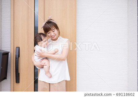 抱著一個嬰兒在我家門口的年輕女子 抱著一個嬰兒在我家門口的年輕女子 69118602