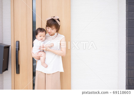 Young woman holding a baby in front of my home Young woman holding a baby in front of my home 69118603