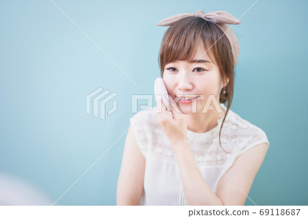 Woman during makeup applying foundation to cheeks 69118687
