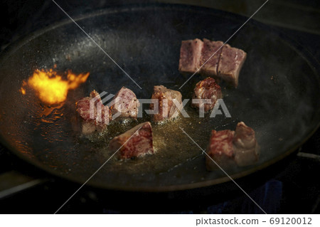 Dice steak flambéed in a frying pan 69120012