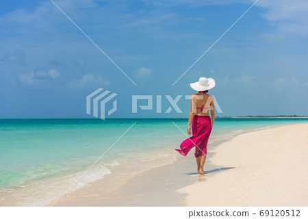 Beach vacation luxury travel to Caribbean destination woman tourist walking on beach with turquoise water Turks and Caicos landscape. Beach vacation luxury travel to Caribbean destination woman tourist walking on beach with turquoise water Turks and Caicos landscape. 69120512