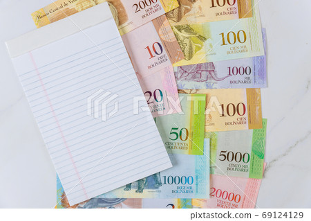 Venezuelan Bolivar banknote with paper currency bills on spiral notepad on a table 69124129