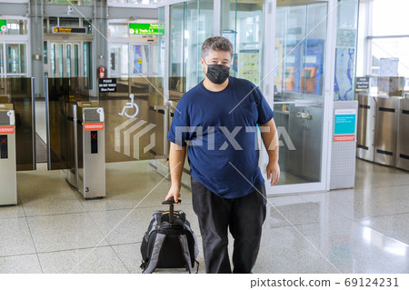 Man traveler with suitcase on wheels wears Man traveler with suitcase on wheels wears 69124231