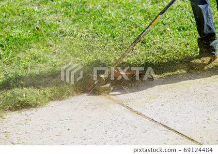 The gardener mows the grass with a lawn mower a 69124484