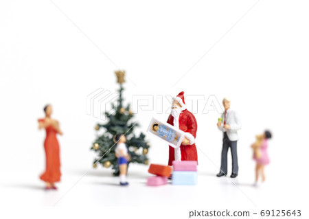 Miniature people : Santa Claus holding gift for happy family , Christmas and Happy New Year concept. Miniature people : Santa Claus holding gift for happy family , Christmas and Happy New Year concept. 69125643