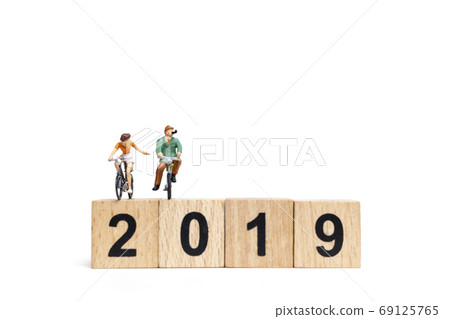 Miniature people : Friend Group ride bicycle with wooden number 2019 , Happy New Year concept. Miniature people : Friend Group ride bicycle with wooden number 2019 , Happy New Year concept. 69125765