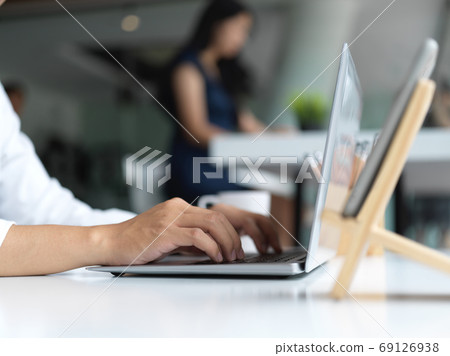 Close-up view of businessman typing on laptop with his worker at 69126938