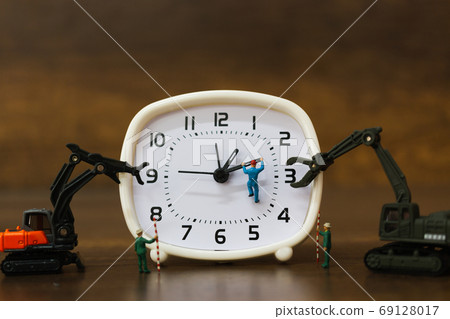 Miniature people : The team is working on an alarm clocks , working time concept Miniature people : The team is working on an alarm clocks , working time concept 69128017