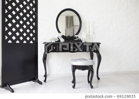 Black boudoir table in a bright room with a white brick wall. Black boudoir table in a bright room with a white brick wall. 69129035