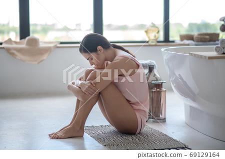 Upset and stressed woman sitting on thefloor of her bathroom 69129164