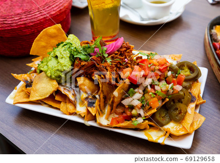 Nachos with meat, vegetables and Guacamole Nachos with meat, vegetables and Guacamole 69129658