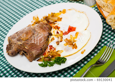 Image of dish of tasty cooked fried pork with fried eggs 69130041