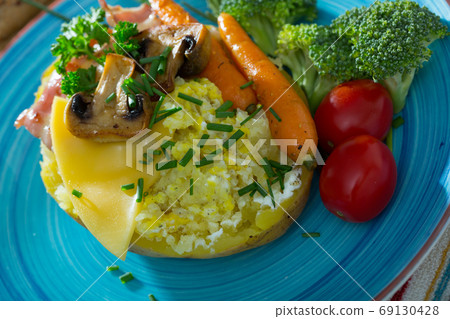 Baked potato with cheese, bacon, mushrooms Baked potato with cheese, bacon, mushrooms 69130428