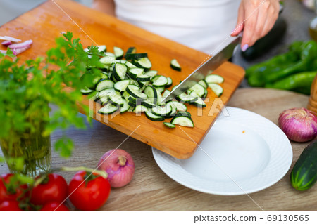 Slicing fresh cucumber on cutting board Slicing fresh cucumber on cutting board 69130565