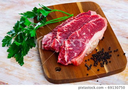 Raw sliced marbled beef meat with parsley and condiments Raw sliced marbled beef meat with parsley and condiments 69130750