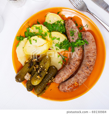 Grilled sausages with boiled potato and pickled cucumbers Grilled sausages with boiled potato and pickled cucumbers 69130984