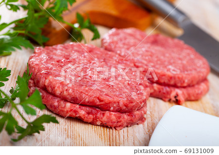 Close up of raw burger cutlet from pork on wooden table Close up of raw burger cutlet from pork on wooden table 69131009