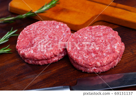 Raw meat burger cutlet with greens on wooden surface Raw meat burger cutlet with greens on wooden surface 69131137