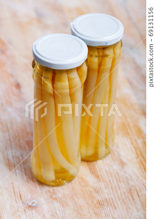 Glass jar with pickled white asparagus on wooden table Glass jar with pickled white asparagus on wooden table 69131156