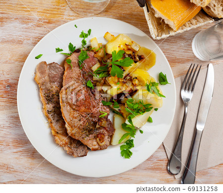Served dish with fried pork, herbs and potatoes Served dish with fried pork, herbs and potatoes 69131258