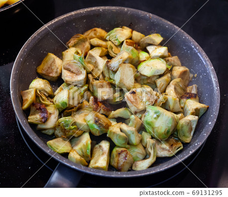 Appetizing artichokes fried in a pan 69131295