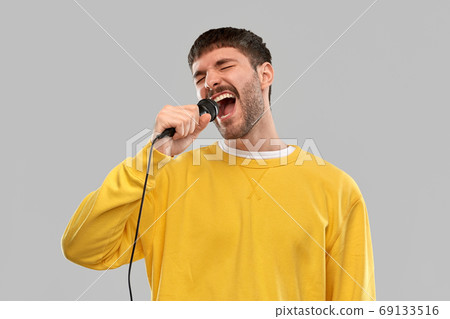 man in yellow sweatshirt with microphone singing 69133516