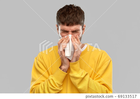 man with paper napkin blowing nose 69133517