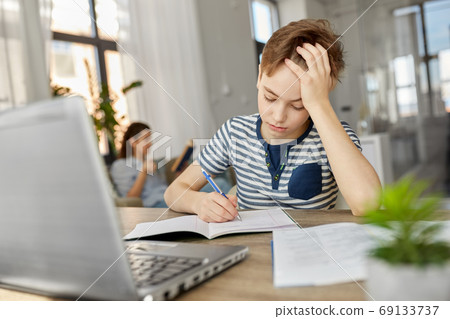 student boy with book writing to notebook at home 69133737
