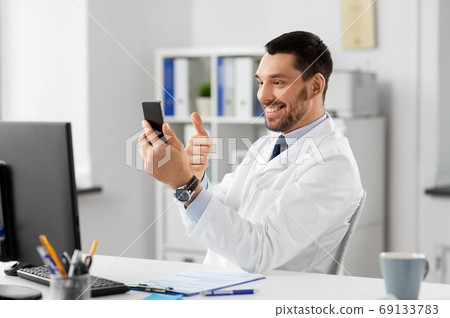 doctor with smartphone having video call at clinic doctor with smartphone having video call at clinic 69133783