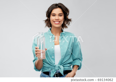 smiling young woman holding water in glass bottle smiling young woman holding water in glass bottle 69134062